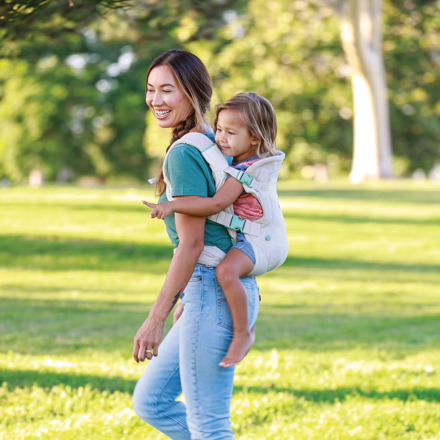 Infantino Flip 4-in-1 convertible baby carrier in cream and teal worn by parent outdoors