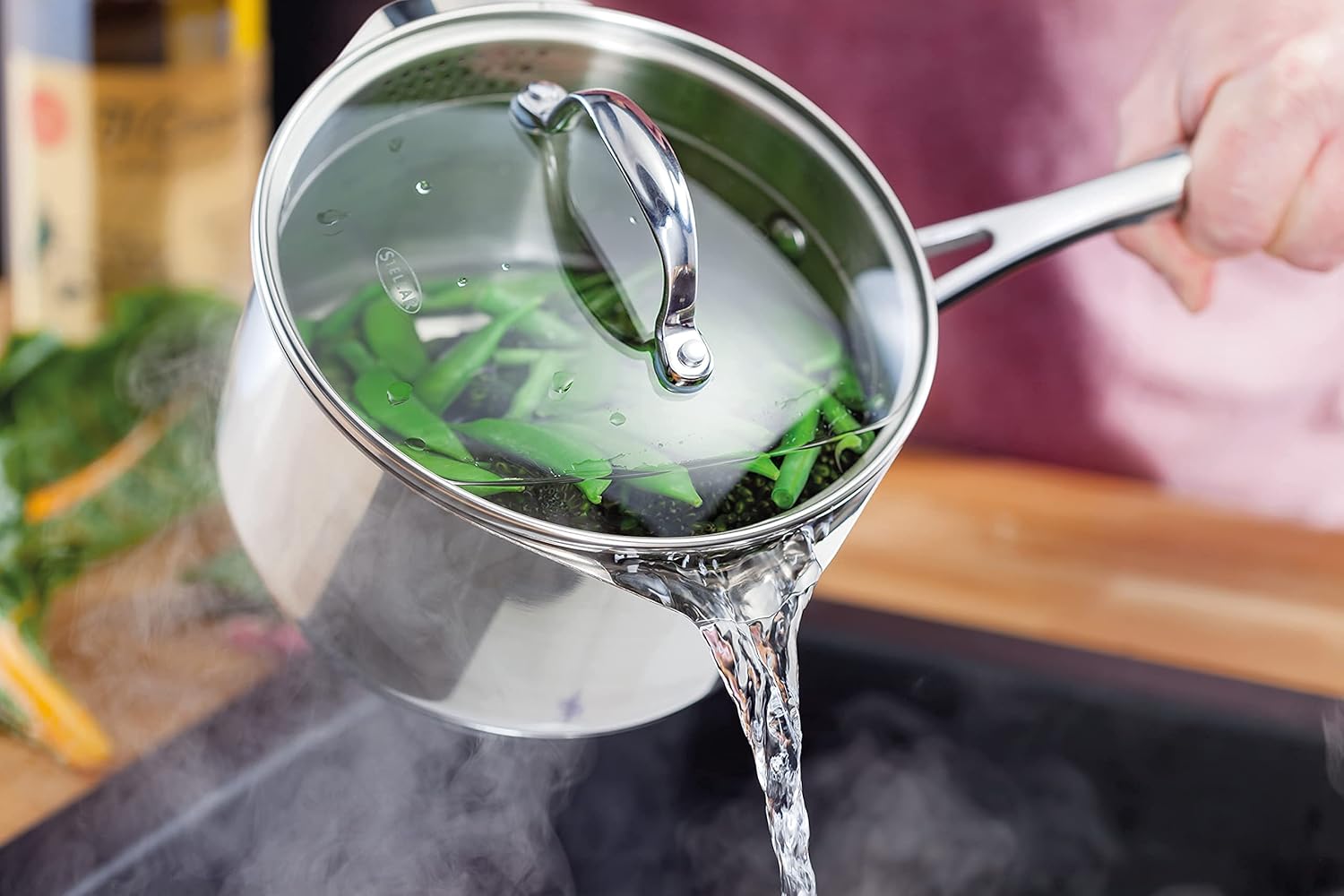 Stellar stainless steel draining saucepan with strainer lid, water pouring from spout